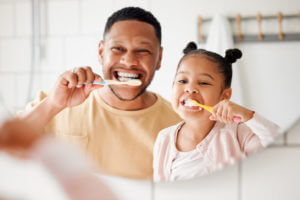 Happy mixed race father and daughter brushing