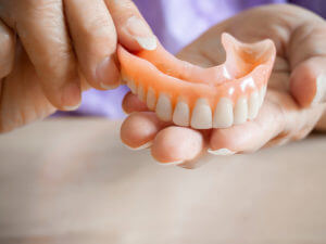 woman holding a denture
