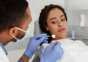 woman looking at dental tools in doctor hands is suffering with dental anxiety