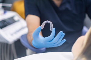rofessional orthodontist showing innovative Jaw aligners to camera