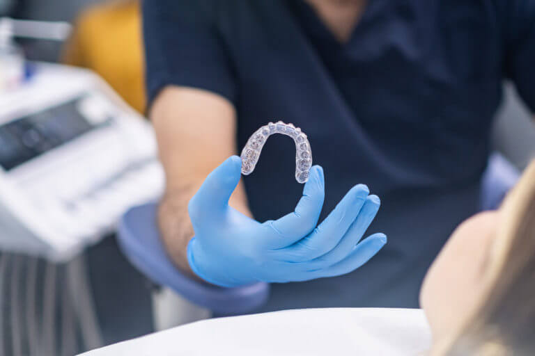 rofessional orthodontist showing innovative Jaw aligners to camera