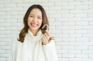 A woman smiling and holding a dental clear braces
