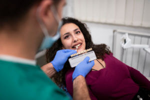 A young woman is getting dental treatment in a dentist's office, where she is about to receive a dental implant.