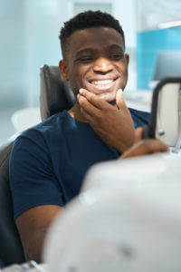 A happy man looking at his healthy teeth and smiling at the result from his teeth whitening.
