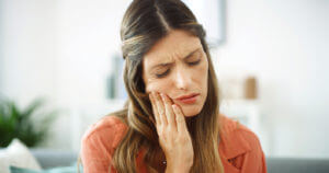 A woman is experiencing toothache at home caused by a root canal injury.