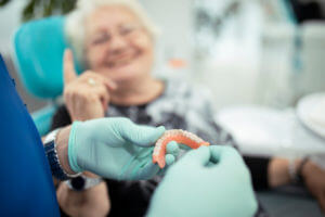 A dentist presents a set of dentures to a patient who is in the process of receiving denture implants.