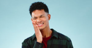 A man experiencing tooth pain, possibly caused by gum disease.