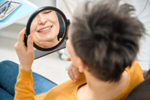 A female patient checking her smile and state of teeth after tooth implant.